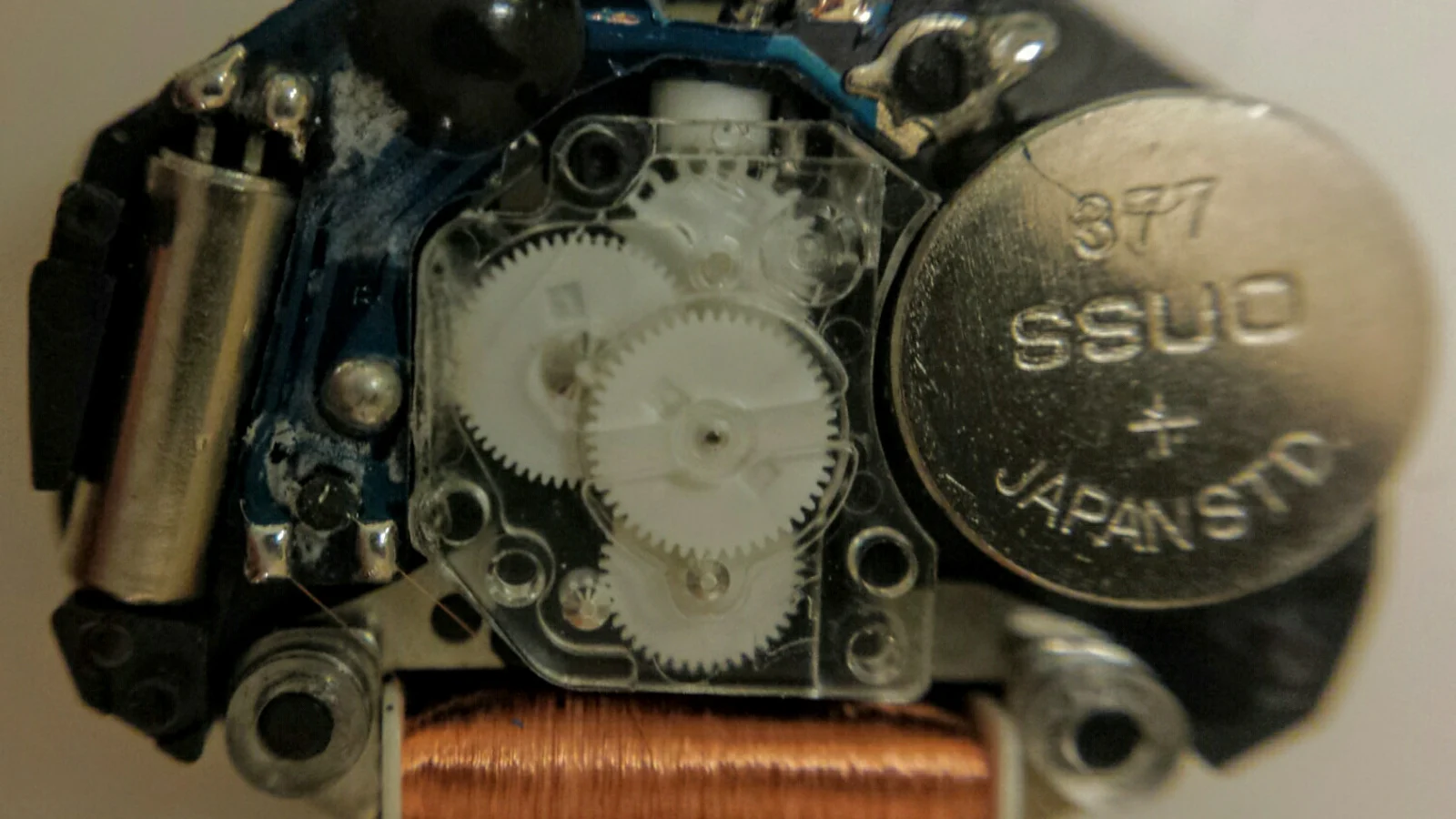 Macro close-up of the internal gear train and small metal components inside a quartz watch mechanism.