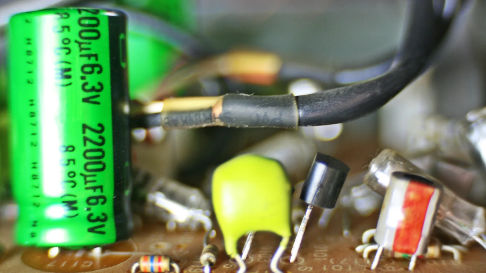 Macro close-up of a circuit board with capacitors, transistors and resistors.